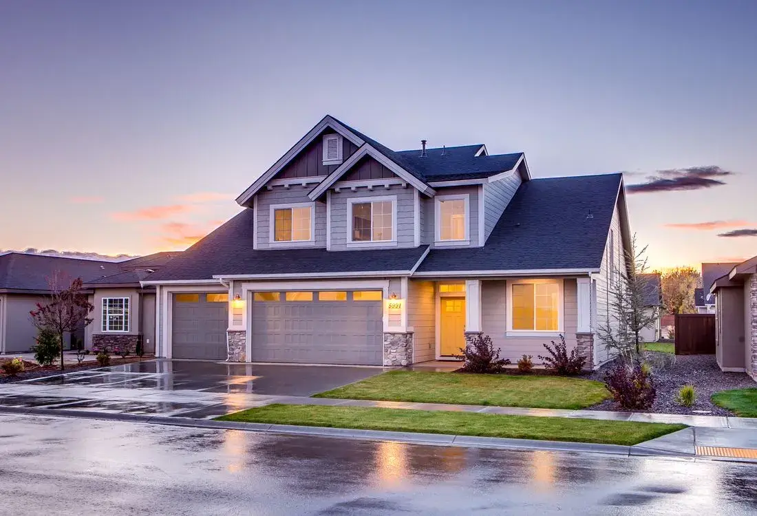 A suburban home with a dark asphalt shingle roof at dusk