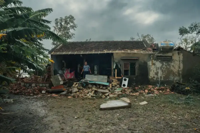 A storm-damaged house with debris scattered around it