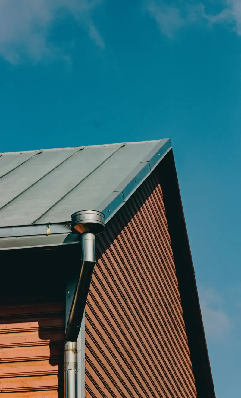 Close-up of a standing-seam metal roof edge on a wooden house