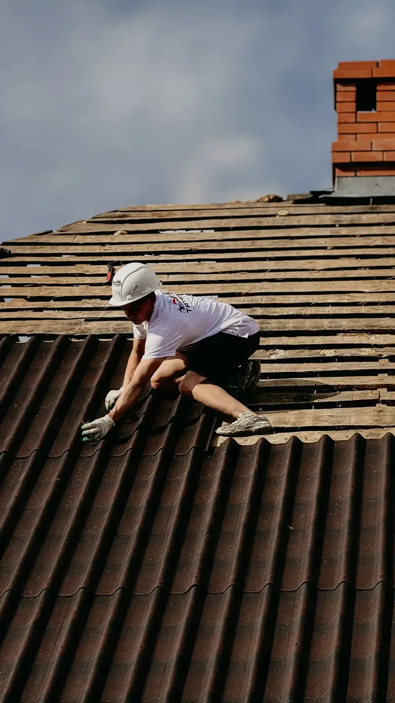 A roofer in a hard hat working on a roof
